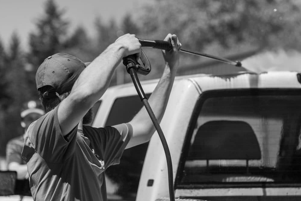 Technician pressure washing a pickup truck