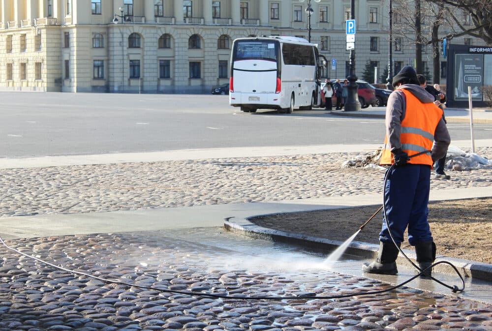 Crew member pressure washing a city street