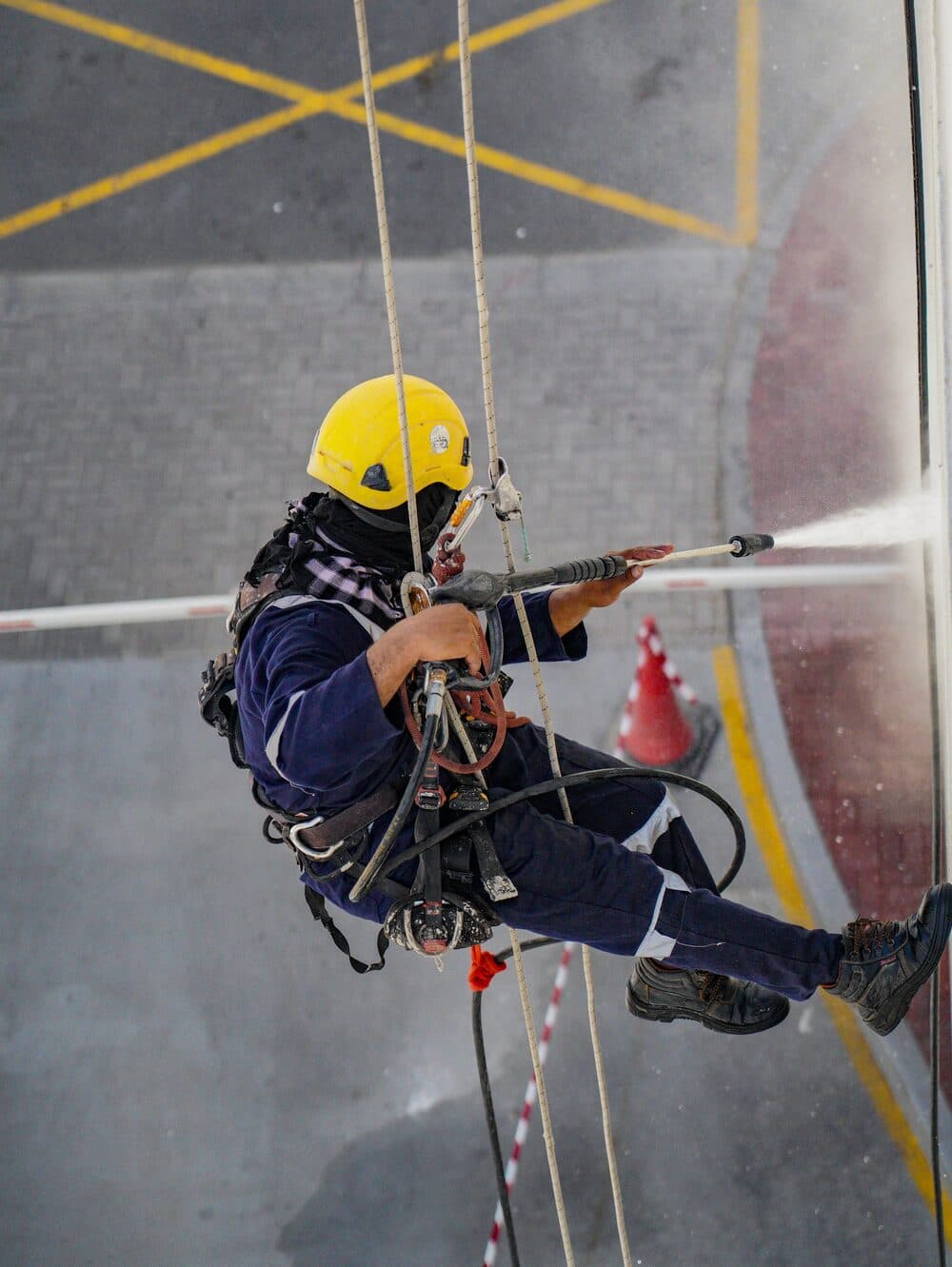 Technician washing high windows on ropes